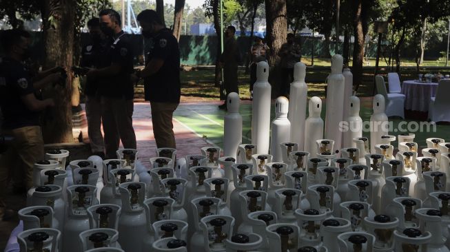 Polisi berdiri di dekat tabung oksigen saat penyerahan barang bukti tabung oksigen hasil pengungkapan kasus tindak kejahatan di Monas, Jakarta, Selasa (27/7/2021). [Suara.com/Angga Budhiyanto]