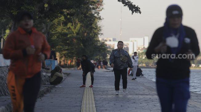 Warga berolahraga di kawasan Danau Sunter, Jakarta, Selasa (27/7/2021). [Suara.com/Angga Budhiyanto]