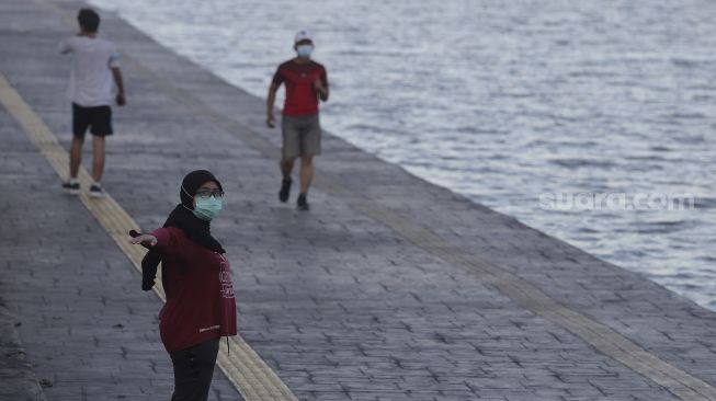 Warga berolahraga di kawasan Danau Sunter, Jakarta, Selasa (27/7/2021). [Suara.com/Angga Budhiyanto]