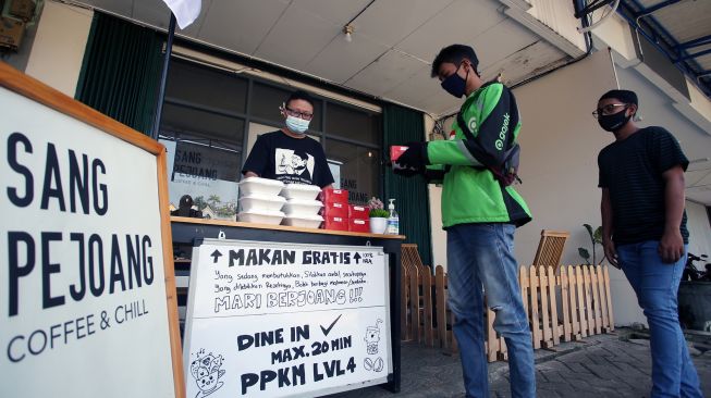 Seorang pemilik kedai kopi memberikan makan siang gratis kepada pengemudi ojek daring di Gading Serpong, Tangerang, Banten, Selasa (27/7/2021). ANTARA FOTO/Muhammad Iqbal