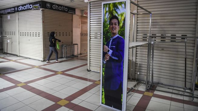 Pengunjung melintas di dekat sejumlah kios yang tutup di Pasar Tanah Abang, Jakarta, Senin (26/7/2021). . ANTARA FOTO/Hafidz Mubarak