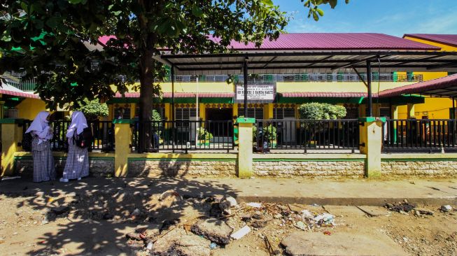 Dua pelajar menunggu jemputan di depan SDN-3 Lhokseumawe, Aceh, Rabu (28/7/2021).  ANTARA FOTO/Rahmad