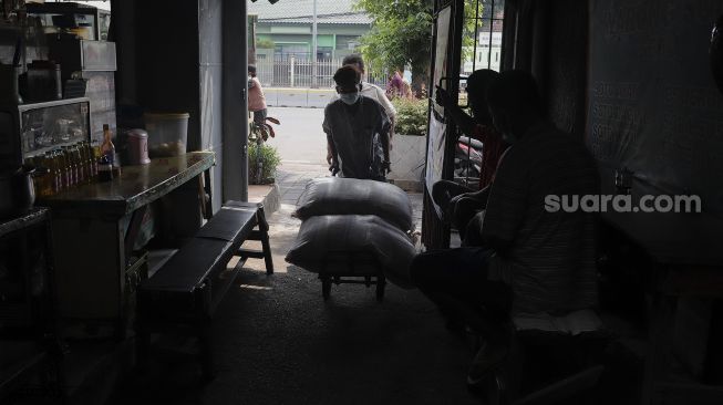 Pengurus RT memindahkan beras yang siap disalurkan kepada warga di RW 03 Kelurahan Tanah Tinggi, Kecamatan Johar Baru, Jakarta, Kamis (29/7/2021). [Suara.com/Angga Budhiyanto]