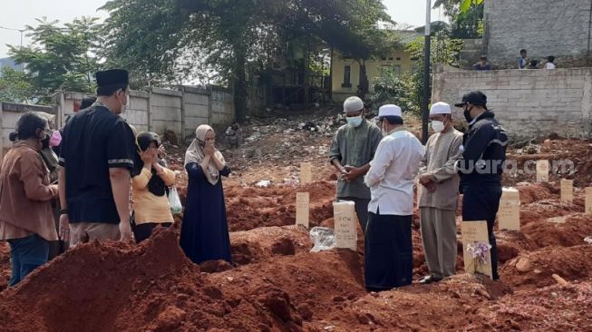 Sejumlah keluarga tengah berdoa usai prosesi pemakaman di lahan zona 2 TPU Jombang, Ciputat, Kota Tangsel, Kamis (29/7/2021). [SuaraJakarta.id/Wivy Hikmatullah]