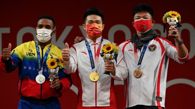 Lifter Indonesia, Rahmat Erwin Abdullah (kanan) meraih medali perunggu di Olimpiade Tokyo. [Vincenzo PINTO / AFP]