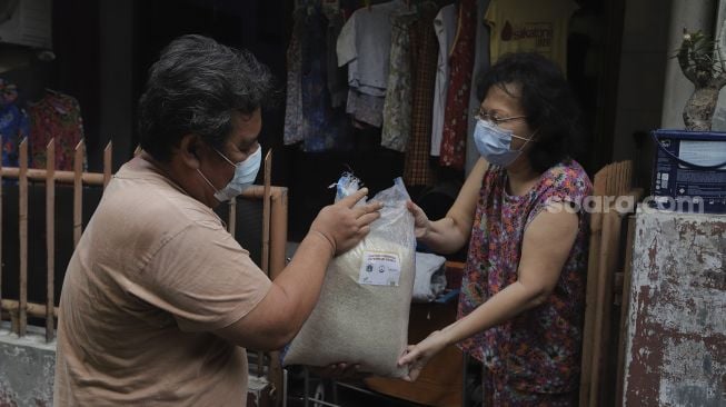 Pengurus RT menyalurkan bantuan sosial non tunai berupa beras kepada warga di RW 03 Kelurahan Tanah Tinggi, Kecamatan Johar Baru, Jakarta, Kamis (29/7/2021). [Suara.com/Angga Budhiyanto]