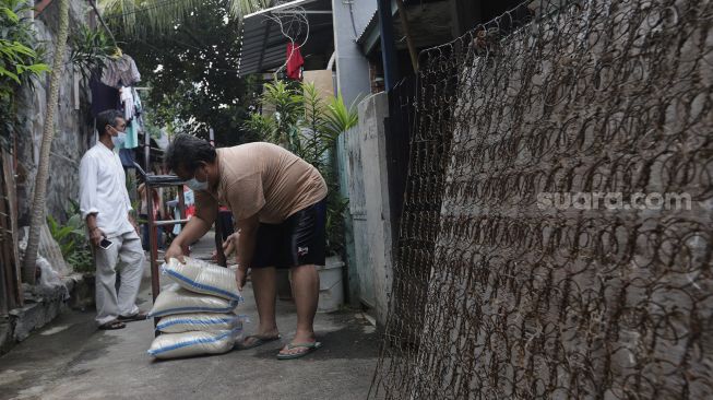 Pengurus RT menyalurkan bantuan sosial non tunai berupa beras kepada warga di RW 03 Kelurahan Tanah Tinggi, Kecamatan Johar Baru, Jakarta, Kamis (29/7/2021). [Suara.com/Angga Budhiyanto]