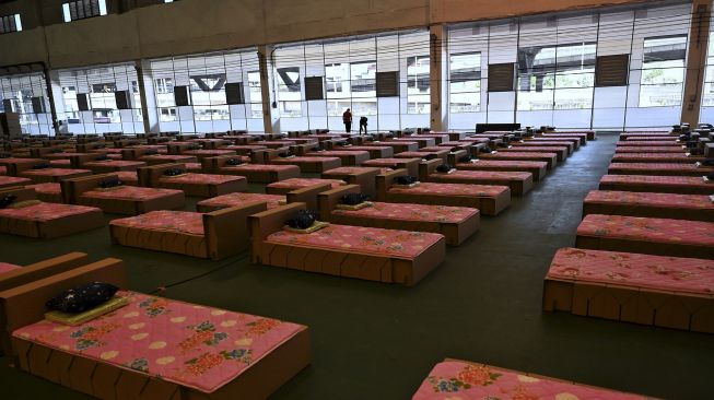 Pekerja menyiapkan kasur dan selimut untuk tempat tidur kardus di rumah sakit lapangan COVID-19 di dalam gudang Bandara Internasional Don Mueang, Bangkok, Thailand, pada (27/7/2021). [Lillian SUWANRUMPHA / AFP]