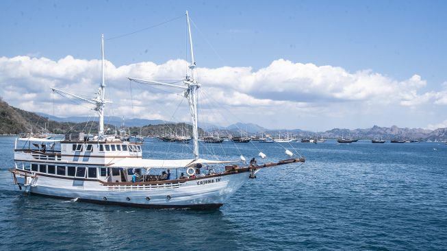 Sebuah kapal wisata pinisi melintas di perairan dekat Dermaga Labuan Bajo, Manggarai Barat, Nusa Tenggara Timur, Jumat (30/7/2021). [ANTARA FOTO/Muhammad Adimaja]