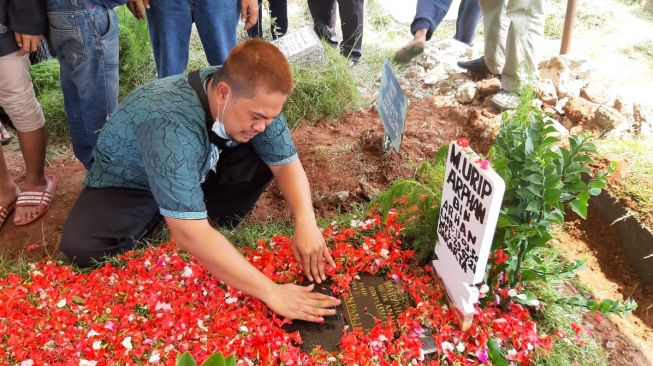 Arif, salah satu putra Urip Arphan menangis di pemakaman sang ayah di TPU Kawi-Kawi, Percetakan Negara, Jakarta Pusat, Jumat (30/7/2021). [Ismail/Suara.com]