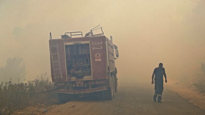 Petugas pemadam kebakaran mencoba memadamkan api di hutan daerah Qubayyat di wilayah terpencil Akkar, Lebanon, pada (29/7/2021). [JOSEPH EID / AFP]