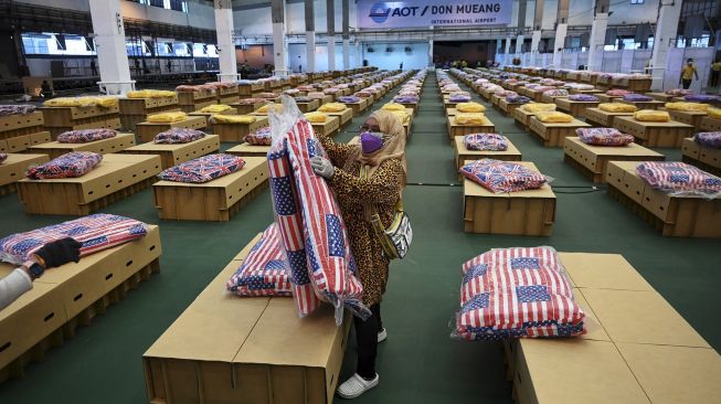 Pekerja menyiapkan kasur dan selimut untuk tempat tidur kardus di rumah sakit lapangan COVID-19 di dalam gudang Bandara Internasional Don Mueang, Bangkok, Thailand, pada (27/7/2021). [Lillian SUWANRUMPHA / AFP]