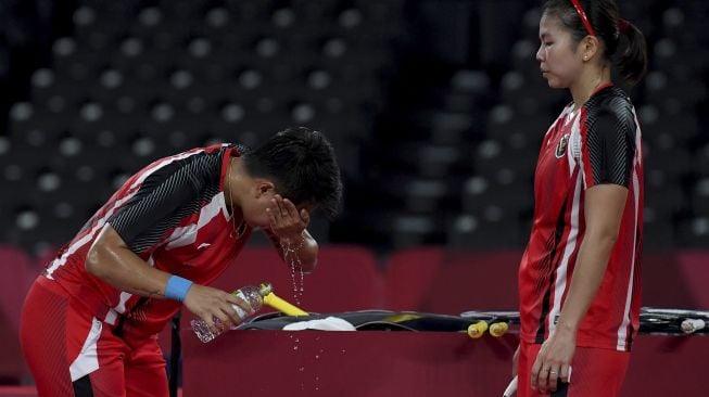 Pebulutangkis ganda putri Indonesia Apriyani Rahayu (kiri) membasuh matanya disaksikan rekannya Greysia Polii saat melawan ganda putri Korea Selatan Lee Sohee/Shin Seungchan dalam semifinal Olimpiade Tokyo 2020 di Musashino Forest Sport Plaza, Tokyo, Jepang, Sabtu (31/7/2021). [ANTARA FOTO/Sigid Kurniawan]