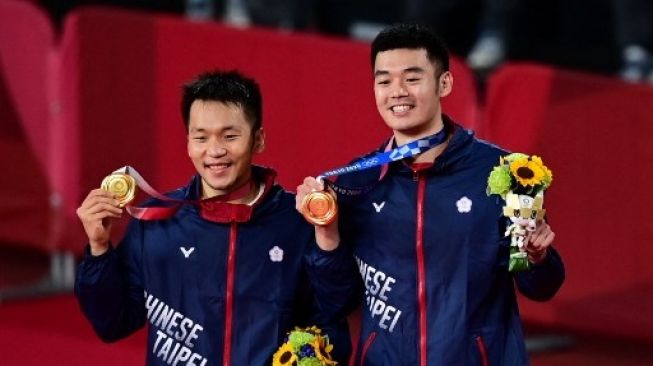 Lee Yang (kiri) dan Wang Chi-lin dari Taiwan berfoto dengan medali emas bulu tangkis ganda putra mereka pada upacara Olimpiade Tokyo 2020 di Musashino Forest Sports Plaza di Tokyo pada 31 Juli 2021.Pedro PARDO / AFP