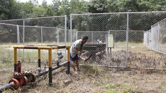 Seorang warga membersihkan rumput di dekat sebuah ladang sumur minyak Blok Rokan areal kerja Tanah Putih Tanjung Melawan Rokan Hilir, Riau, Sabtu (31/7/2021). [ANTARA FOTO/Aswaddy Hamid]