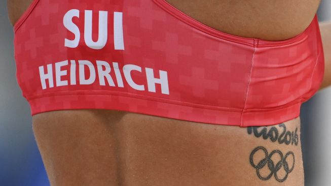 Tato Olimpiade Rio 2016 terlihat di tulang rusuk Joana Heidrich dari Swiss saat pertandingan voli pantai putri antara Swiss dan Jerman selama Olimpiade Tokyo 2020 di Shiokaze Park, Tokyo pada (24/7/2021). [Angela WEISS / AFP]