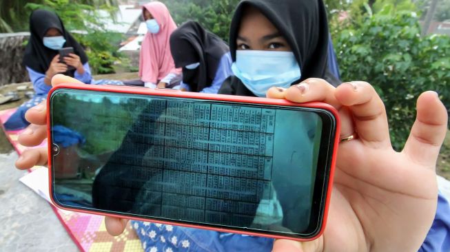 Pelajar menunjukkan bahan pembelajaran dalam jaringan (daring) di atas atap rumah warga di Desa Meuria Paloh, Aceh, Sabtu (31/7/2021).  ANTARA FOTO/Rahmad