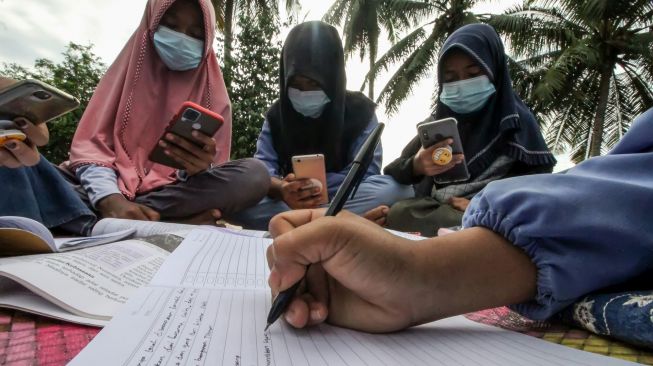 Sejumlah pelajar mengikuti proses belajar mengajar dalam jaringan (daring) di atas atap rumah warga di Desa Meuria Paloh, Aceh, Sabtu (31/7/2021). ANTARA FOTO/Rahmad