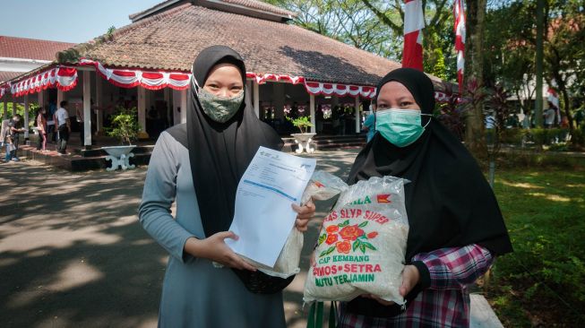 Warga menunjukkan beras bantuan saat mengikuti vaksinasi COVID-19 di Pendopo Kabupaten Lebak, Banten, Senin (2/8/2021).  ANTARA FOTO/Muhammad Bagus Khoirunas