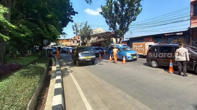 Aparat kepolisian saat memeriksa kendaraaan yang melintas di pos penyekatan PPKM di Lenteng Agung. (Suara.com/Arga)