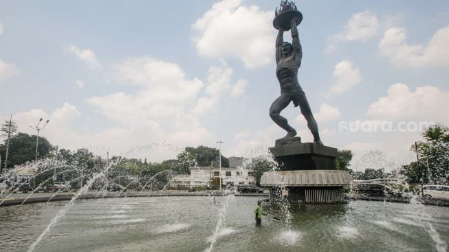 Petugas Dinas Pertamanan dan Kehutanan DKI Jakarta melakukan perwatan rutin kolam air mancur Patung Pemuda Membangun di Bundaran Senayan, Jakarta Pusat, Senin (2/8/2021). [Suara.com/Alfian Winanto]