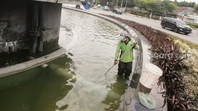 Petugas Dinas Pertamanan dan Kehutanan DKI Jakarta membersihkan bagian dasar kolam air mancur Patung Pemuda Membangun di Bundaran Senayan, Jakarta Pusat, Senin (2/8/2021). [Suara.com/Alfian Winanto]