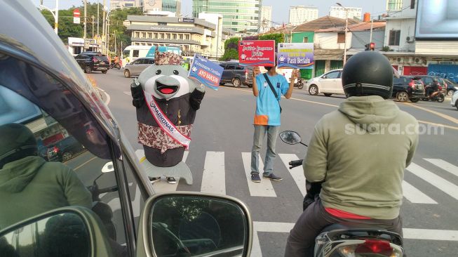 Maskot Hari Konsumen Nasional (Harkonas) Si Enda melakukan aksi kampanye kepada pengendara di kawasan Tugu Tani, Jakarta Pusat, Selasa (3/8/2021). [Suara.com/Alfian Winanto]