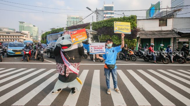 Maskot Hari Konsumen Nasional (Harkonas) Si Enda melakukan aksi kampanye kepada pengendara di kawasan Tugu Tani, Jakarta Pusat, Selasa (3/8/2021). [Suara.com/Alfian Winanto]