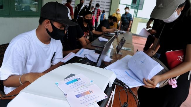 Petugas mencetak kartu sertifikat vaksinasi COVID-19 pesanan warga saat kegiatan vaksinasi COVID-19 massal di Denpasar, Bali, Selasa (3/8/2021). ANTARA FOTO/Fikri Yusuf