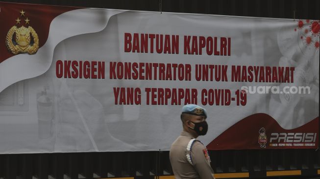 Petugas kepolisian berdiri di dekat truk yang membawa bantuan 1.000 oksigen konsentrator untuk warga yang terpapar COVID-19 di Mabes Polri, Jakarta, Selasa (3/8/2021). [Suara.com/Angga Budhiyanto] 