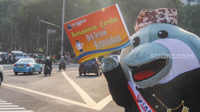 Maskot Hari Konsumen Nasional (Harkonas) Si Enda melakukan aksi kampanye kepada pengendara di kawasan Tugu Tani, Jakarta Pusat, Selasa (3/8/2021). [Suara.com/Alfian Winanto]