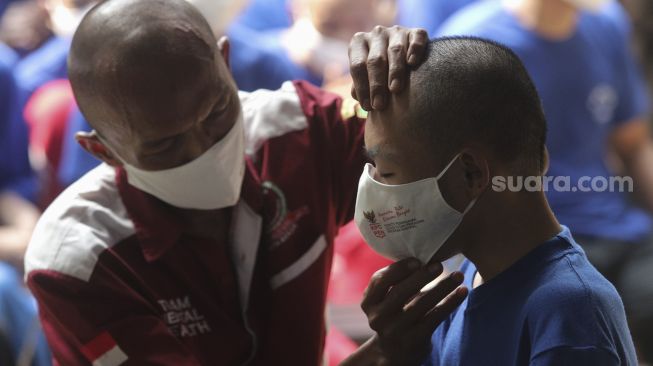 Petugas memasangkan masker kepada pasien ODGJ (Orang Dengan Gangguan Jiwa) sebelum mendapatkan vaksinasi COVID-19 di Yayasan Jamrud Biru, Bekasi, Jawa Barat, Rabu (4/8/2021). [Suara.com/Angga Budhiyanto]