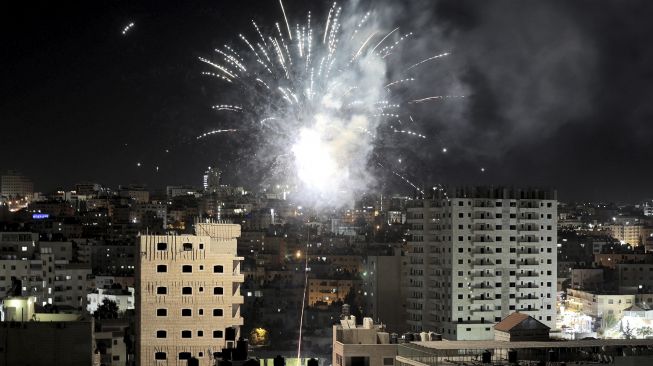 Kembang api menerangi langit saat keluarga Palestina merayakan anak-anak mereka lulus ujian akhir sekolah menengah yang dikenal sebagai "Tawjihi" di kota Ramallah , Tepi Barat, Palestina, pada (3/8/2021). [ABBAS MOMANI / AFP]