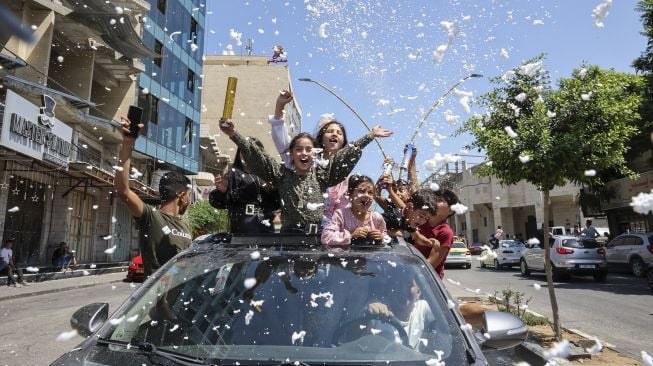 Siswa sekolah menengah Palestina merayakan kelulusan ujian akhir mereka yang dikenal sebagai "Tawjihi" di kota Hebron, Tepi Barat, Palestina, pada (3/8/2021). [HAZEM BADER / AFP]