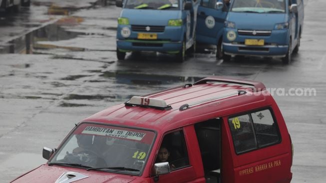 Penumpang menaiki angkutan umum kota (angkot) di Terminal Kampung Rambutan, Jakarta, Kamis (5/8/2021). [Suara.com/Angga Budhiyanto]