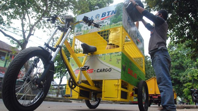 Petugas Dinas Lingkungan Hidup (DLH) Kota Bogor memasukkan sampah kedalam sepeda listrik pengangkut sampah di jalan Paledang, Kota Bogor, Jawa Barat, Rabu (4/8/2021).  ANTARA FOTO/Arif Firmansyah