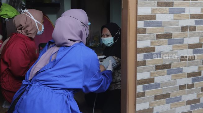 Relawan memeriksa kesehatan ibu menyusui penyintas COVID-19 di RW 07 Kelurahan Tengah, Kramat Jati, Jakarta Timur, Kamis (5/8/2021). [Suara.com/Angga Budhiyanto]