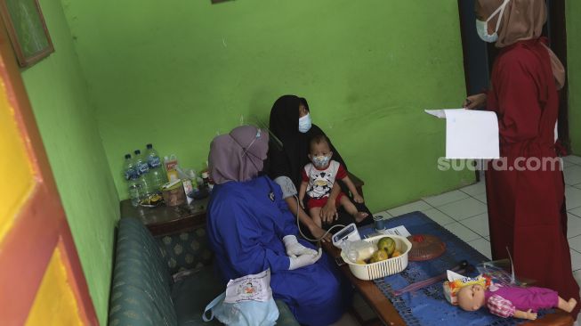 Relawan memeriksa kesehatan ibu menyusui penyintas COVID-19 di RW 07 Kelurahan Tengah, Kramat Jati, Jakarta Timur, Kamis (5/8/2021). [Suara.com/Angga Budhiyanto]