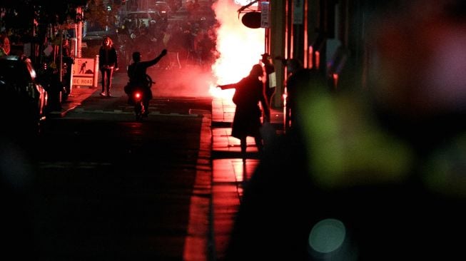 Pengunjuk rasa menyalakan suar ketika memprotes perpanjangan lockdown atau penguncian ketat di Melbourne, Australia, Kamis (5/8/2021).  [AFP Foto]
