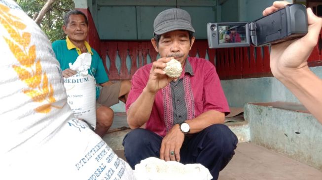 Warga penerima beras bantuan PPKM Level 4 mengeluhkan kondisi beras yang menguning dan menggumpal seperti batu (BantenHits.com/Engkos Kosasih)