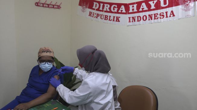 Vaksinator menyuntikkan vaksin COVID-19 dosis ketiga atau booster kepada tenaga kesehatan di Rumah Sakit Umum Daerah (RSUD) Matraman, Jakarta, Jumat (6/8/2021). [Suara.com/Angga Budhiyanto]