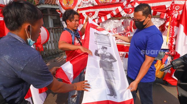 Warga membeli bendera merah putih bergambar Ir. Soekarno di Jalan Matraman Raya, Jatinegara, Jakarta Timur, Minggu (8/8/2021). [Suara.com/Alfian Winanto]