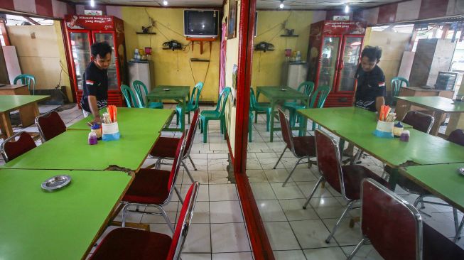 Pekerja merapikan meja salah satu rumah makan di Terminal Kalideres, Jakarta, Sabtu (7/8/2021). ANTARA FOTO/Rivan Awal Lingga