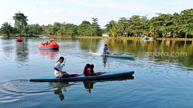 Pengujung saat menikmati berlayar di Danau Ali menggunakan perahu kano.[Suara.com/ Panji Ahmad Syuhada]