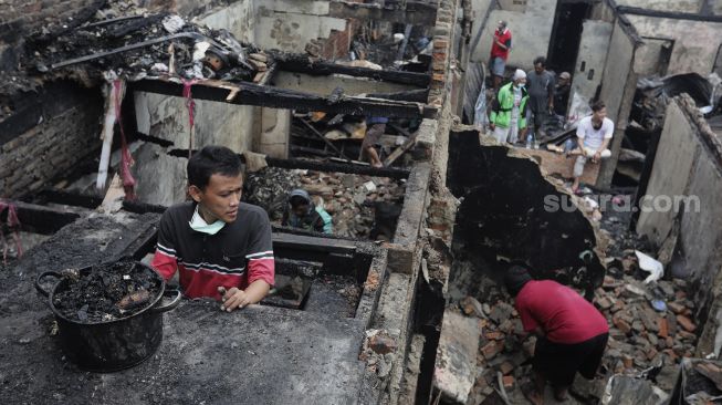 Warga mencari barang yang masih bisa digunakan pascakebakaran di kawasan Grogol Petamburan, Jakarta, Selasa (10/8/2021). [Suara.com/Angga Budhiyanto]