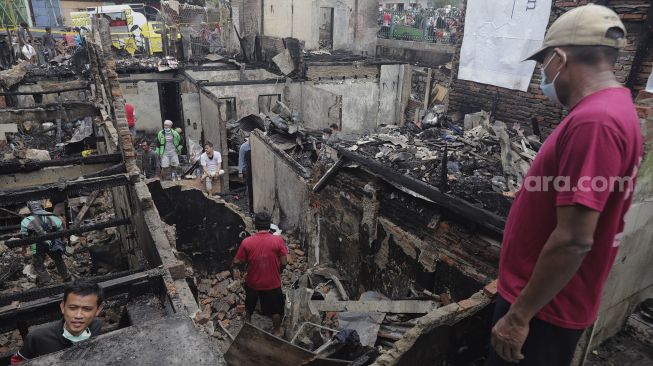 Warga mencari barang yang masih bisa digunakan pascakebakaran di kawasan Grogol Petamburan, Jakarta, Selasa (10/8/2021). [Suara.com/Angga Budhiyanto]