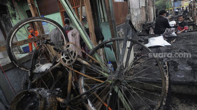 Warga mencari barang yang masih bisa digunakan pascakebakaran di kawasan Grogol Petamburan, Jakarta, Selasa (10/8/2021). [Suara.com/Angga Budhiyanto]