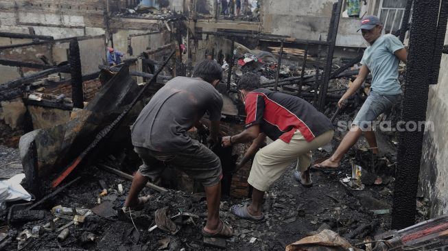 Warga mencari barang yang masih bisa digunakan pascakebakaran di kawasan Grogol Petamburan, Jakarta, Selasa (10/8/2021). [Suara.com/Angga Budhiyanto]