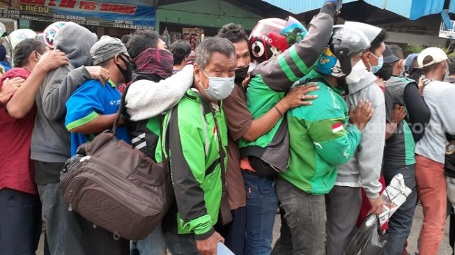 Kerumunan warga saat mengantre sembako yang dibagikan Presien Jokowi di Terminal Grogol, Jakbar. (Suara.com/Yaumal)