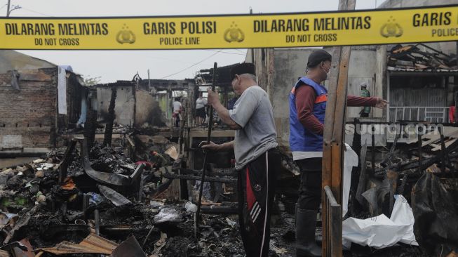 Warga mencari barang yang masih bisa digunakan pascakebakaran di kawasan Grogol Petamburan, Jakarta, Selasa (10/8/2021). [Suara.com/Angga Budhiyanto]